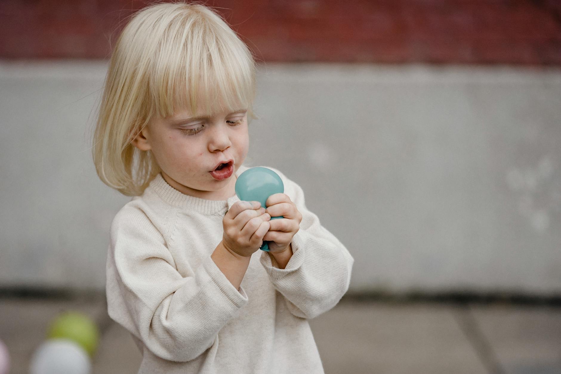adorable girl playing with balloon on street